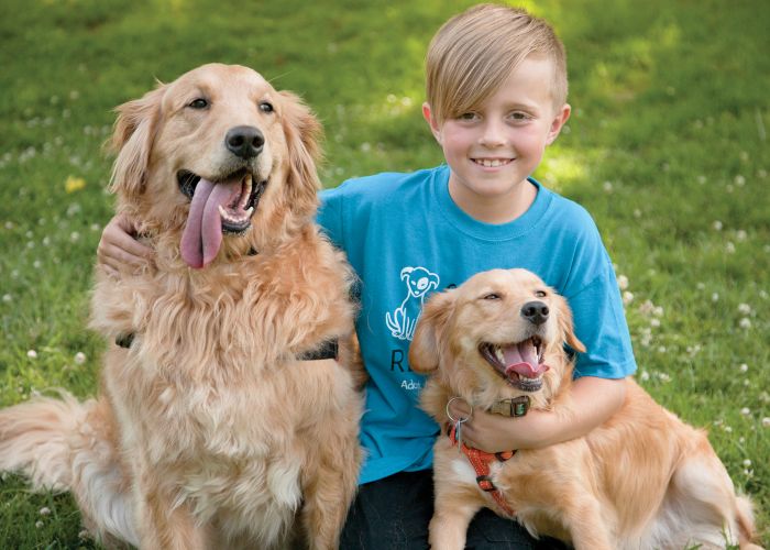 a boy kneeling with two dogs